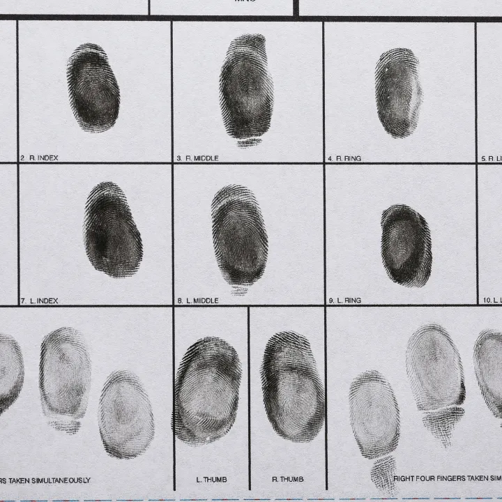 A fingerprint card displaying individual inked fingerprints. The FBI FD-258 fingerprint card shows prints for each finger on both hands, labeled as R. INDEX, R. MIDDLE, R. RING, L. INDEX, L. MIDDLE, L. RING, L. THUMB, and R. THUMB; some squares contain multiple simultaneous prints.